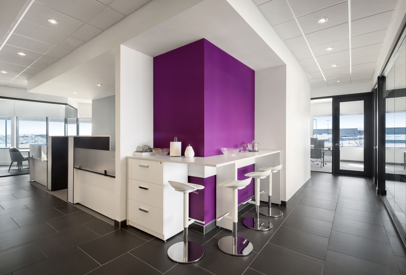 Coffee bar at Medicom offices with white chairs and cabinets and purple accent wall.