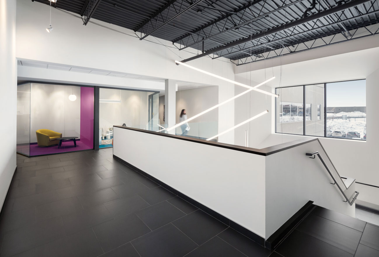 White painted mezzanine with glass cube quiet room with fuscia wall and floor and yellow tub chair.